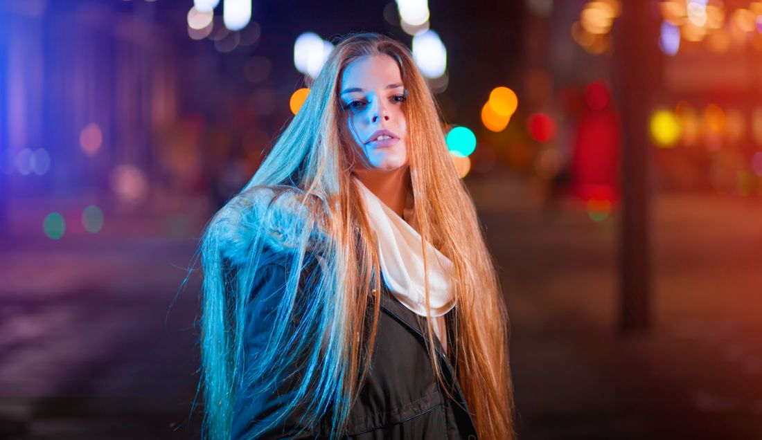 Moody black-and-white night portrait against brick