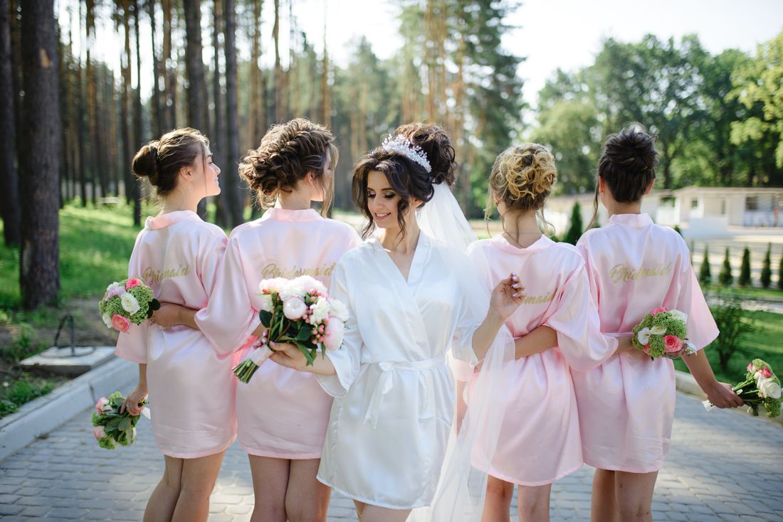 Bride and bridesmaids in pink satin robes with bouquets