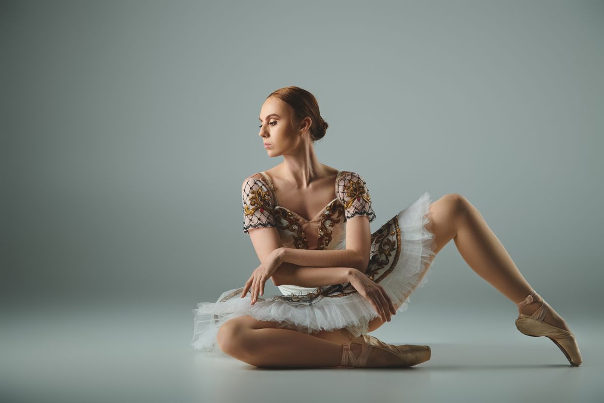 Dancer in a gold ballet costume seated
