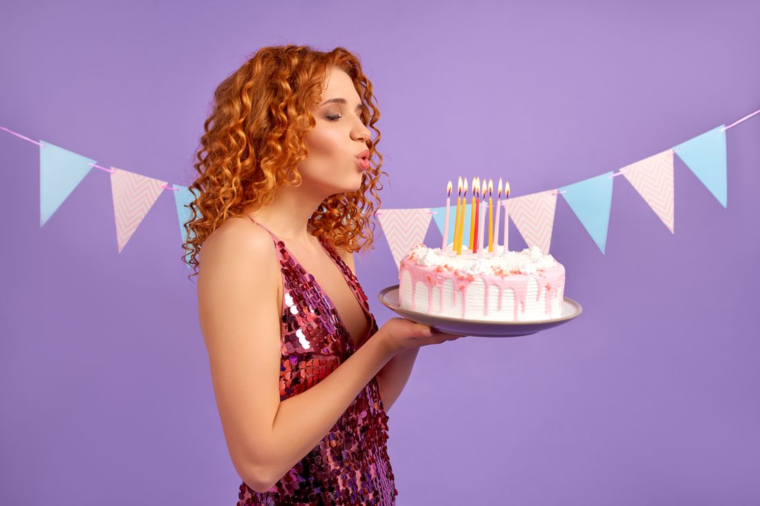 Model blowing out candles on a birthday cake