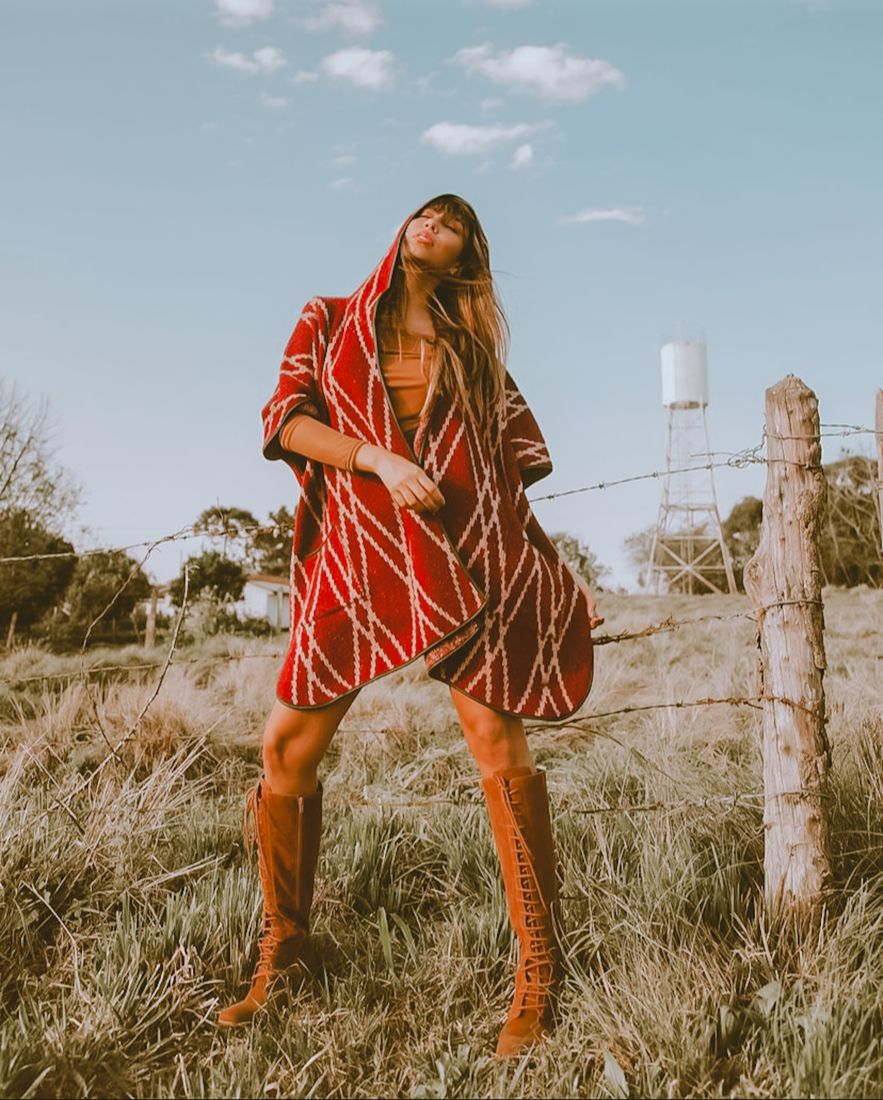 Model in a patterned coat and high boots in a golden field