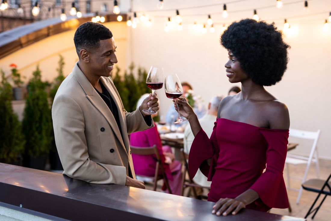 Couple toasting wine at a rooftop garden dinner