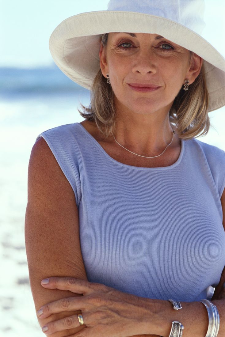 Elegant woman in a white sun hat by the shore