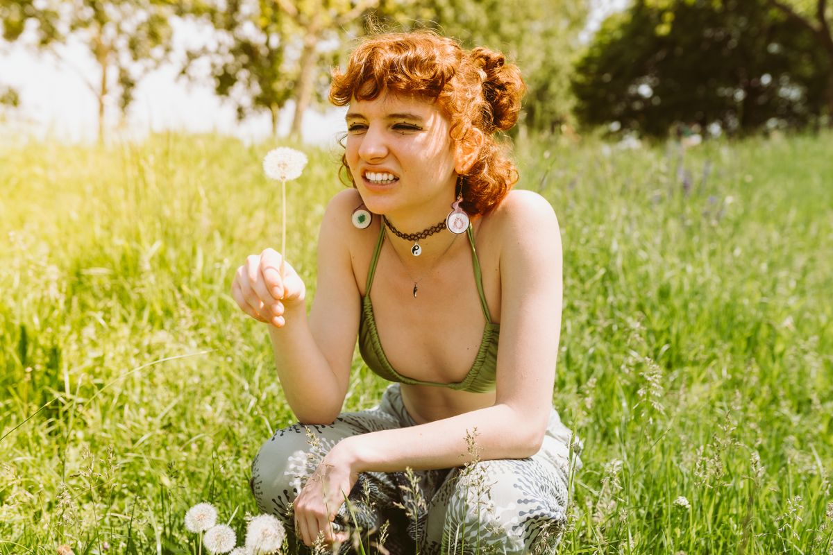 Woman with a dandelion in a sunlit grassy field