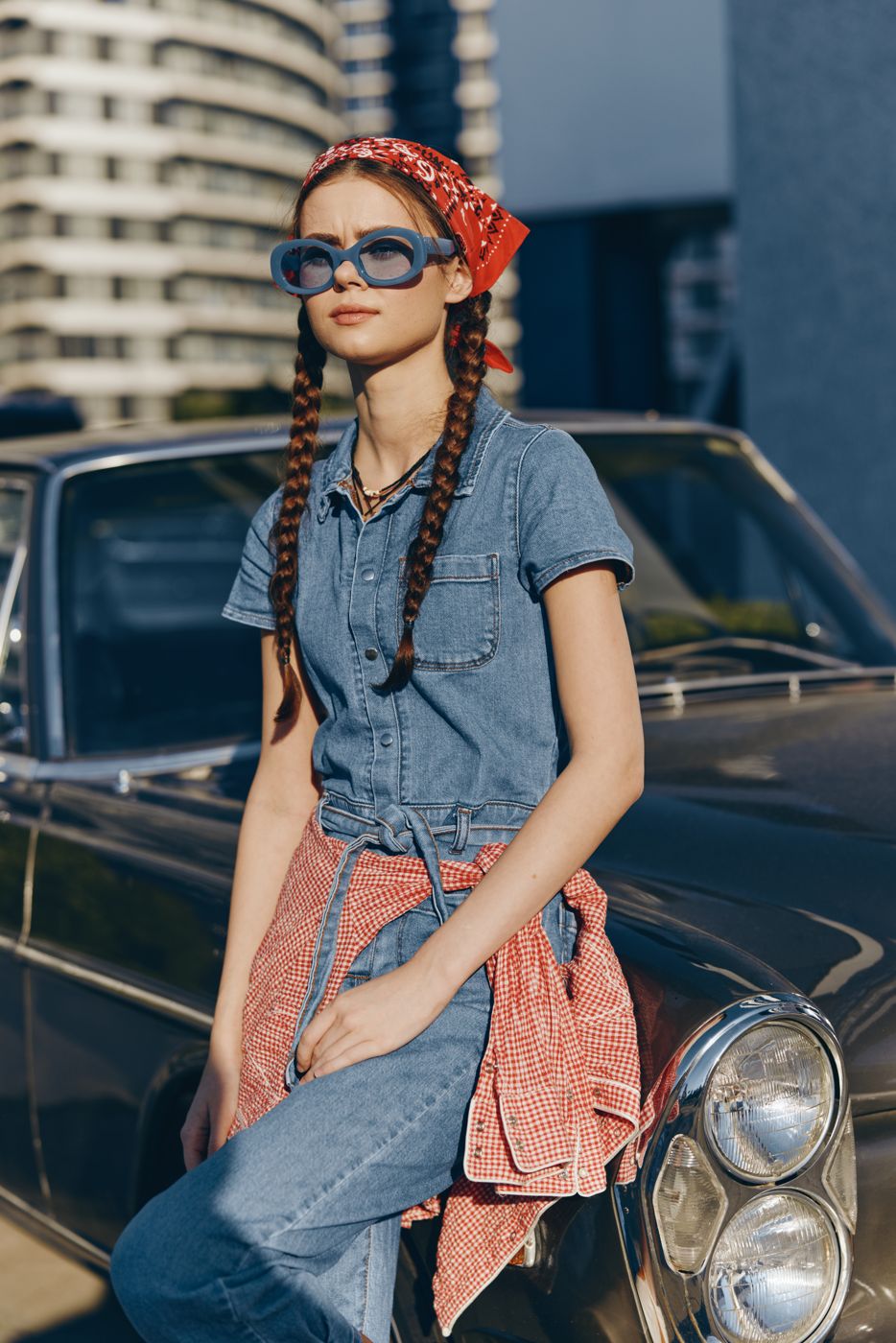 Model in a denim jumpsuit posing against a wall