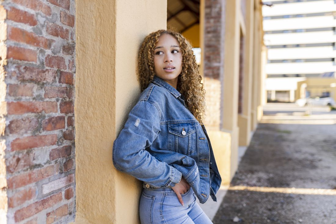 Model leaning on a wall in a denim outfit