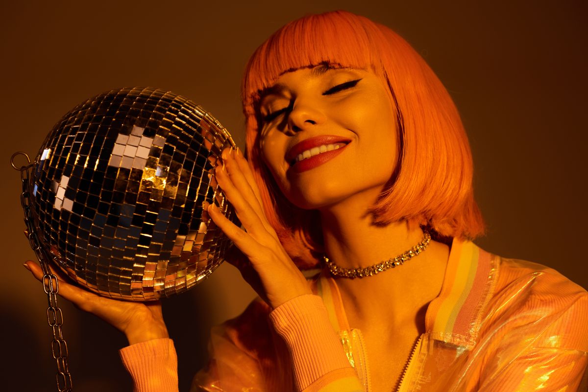 Model with retro orange hair holding a disco ball
