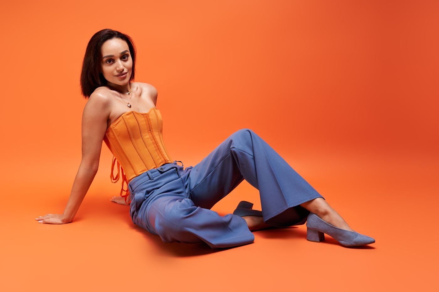 Model in an orange corset and blue trousers