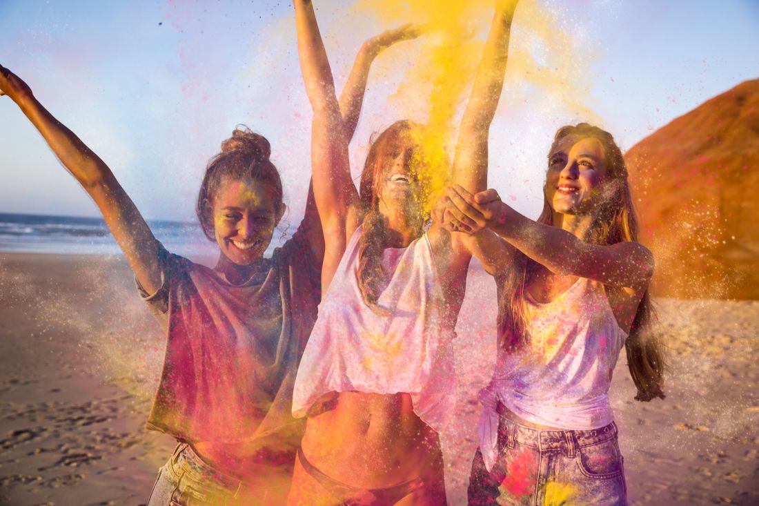 Friends throwing holi color powder on a beach