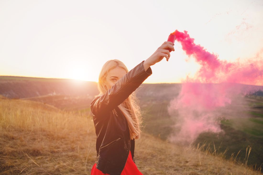 Pink smoke bomb held aloft in a golden field