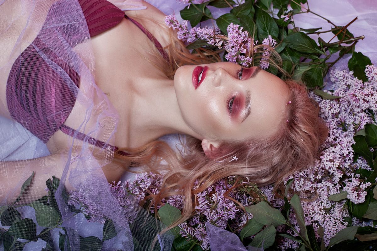 Model with floral adornments lying among flowers