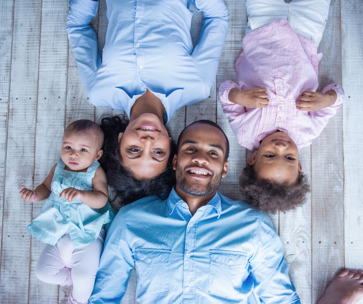 Smiling family lying together on a wooden floor, shot from above