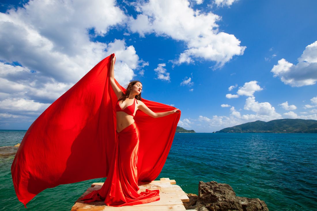 Red flying dress billowing on a rocky coast