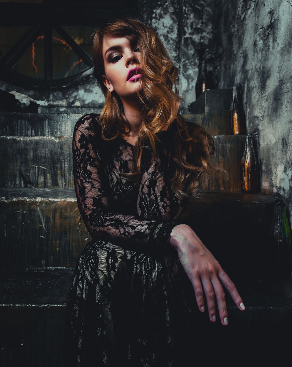 Model in a black lace dress on a stone staircase