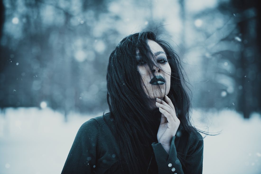 Gothic look with black hair in a snowy forest