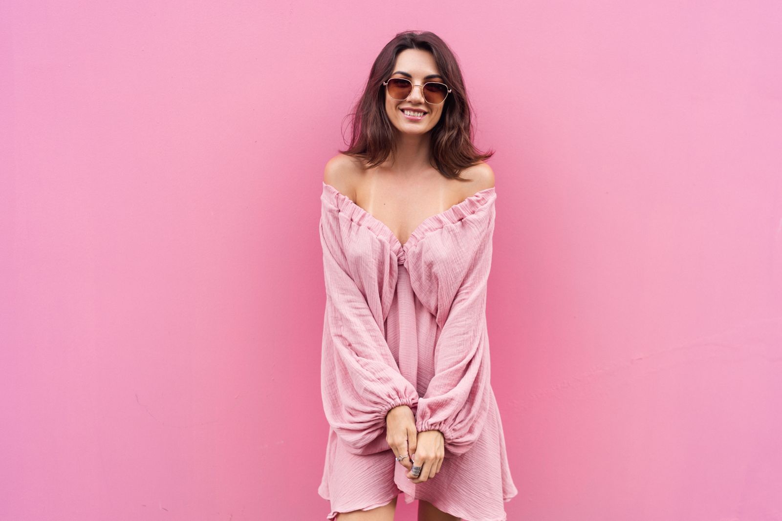 Woman in a pink dress by a pink wall