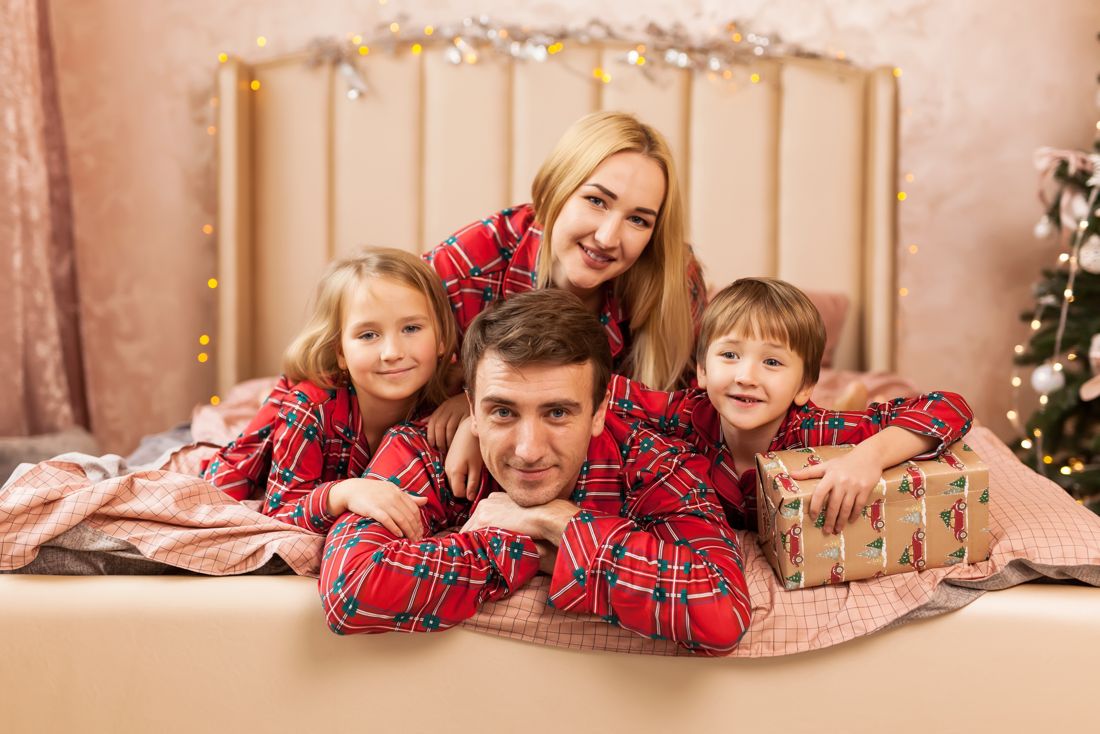 Family lying on a bed with a Christmas present