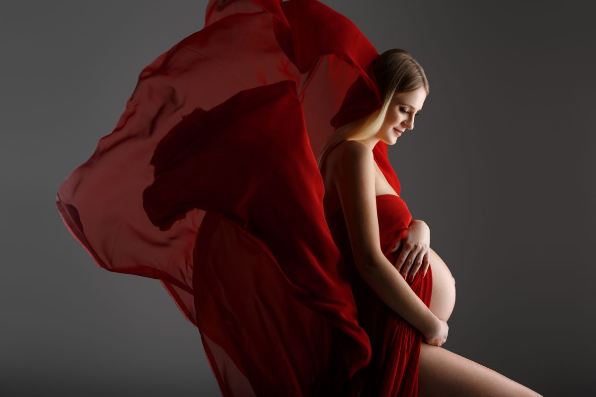 Expecting mother draped in flowing red fabric