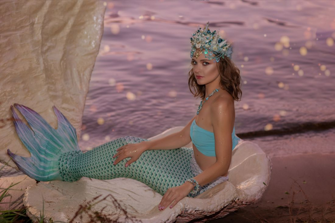 Mermaid tail and crown posed on a shell at the beach