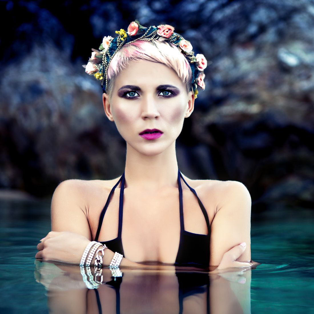 Blonde in a flower wreath reflected in dark water
