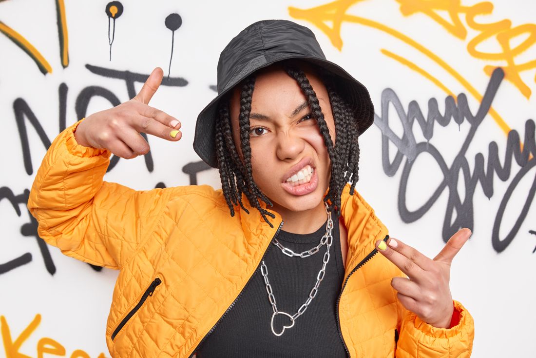 90s hip-hop styling with bucket hat and chains against a graffiti wall