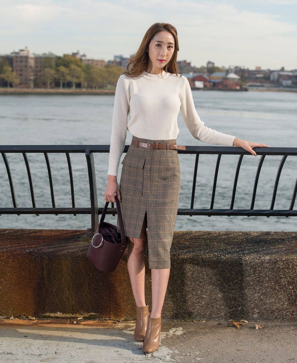Model in a tailored skirt and cream blouse by the river