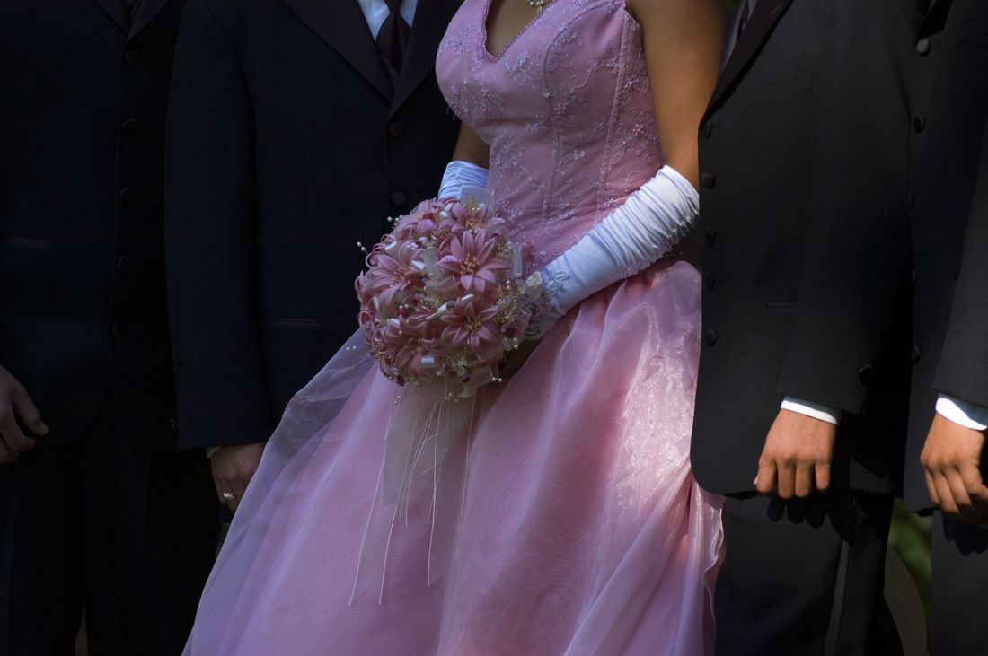 Prom queen in a pink gown with a group in suits