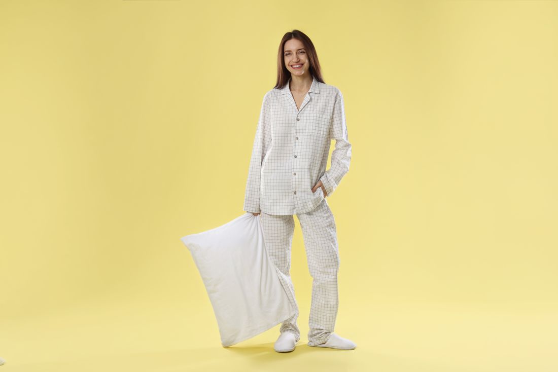 Smiling model in checkered pajamas holding a pillow