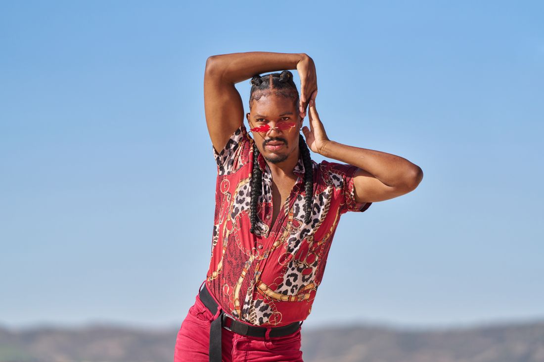 Man in a red shirt posing outdoors against blue sky