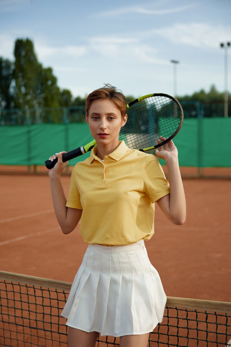 Player in a yellow polo and white skirt on a court