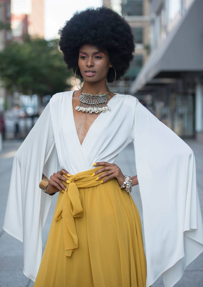 Model in a dramatic white cape top and marigold skirt in the city