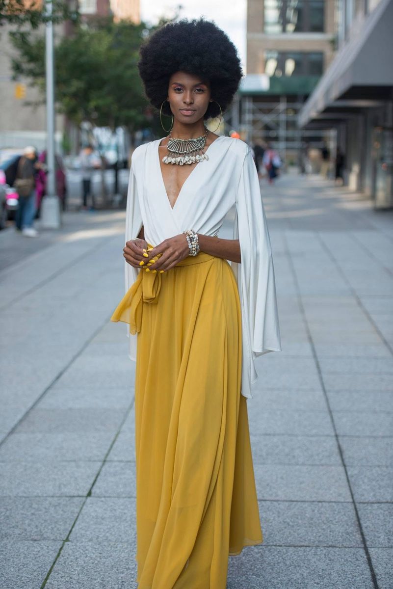 Model in a yellow maxi skirt and white top on a city street