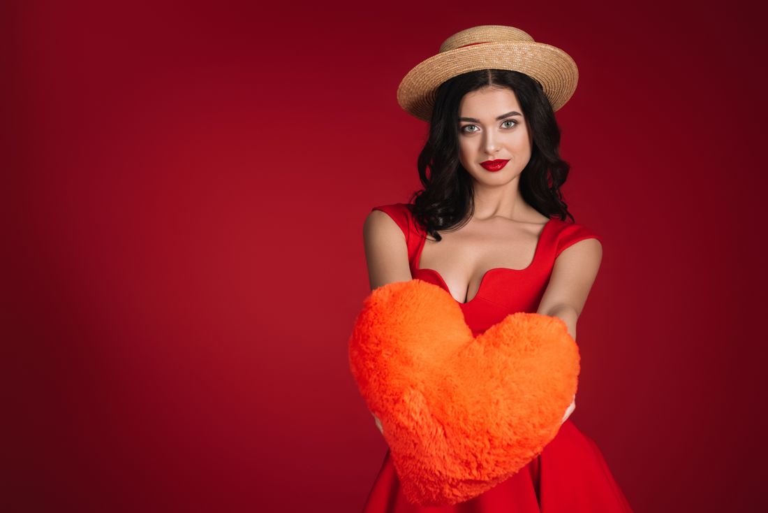 Red dress holding a heart pillow on deep red