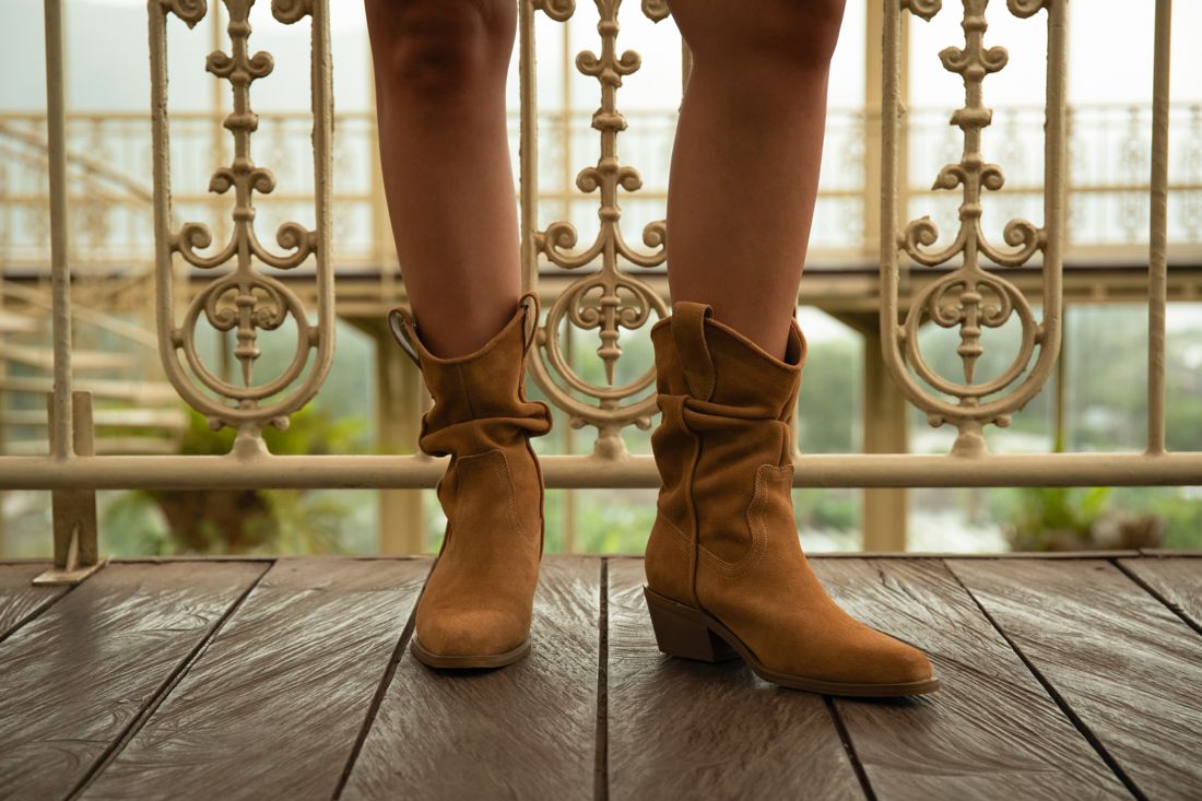 Brown western boots detail on a wooden balcony
